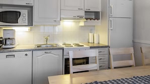 A compact kitchen with a microwave, stove, and sink. There is a coffee maker and a chair visible. - Lepolinna b by Interhome (Nilsiä)