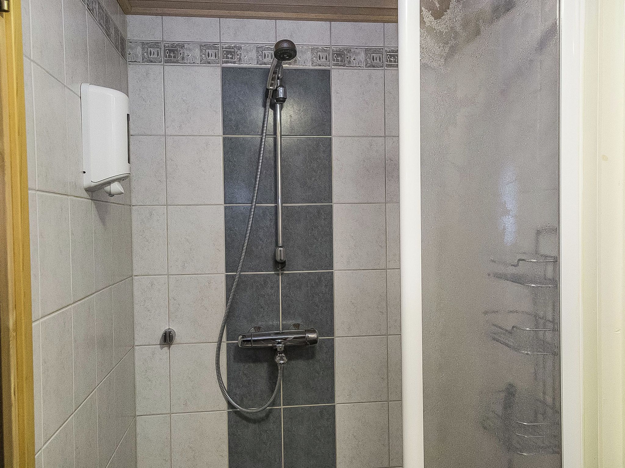 Eine Dusche mit Handbrause und Armaturen an der Wand.