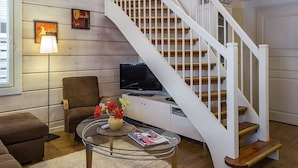 A living room with a staircase, a television, a sofa, and a coffee table. - Lepolinna b by Interhome (Nilsiä)