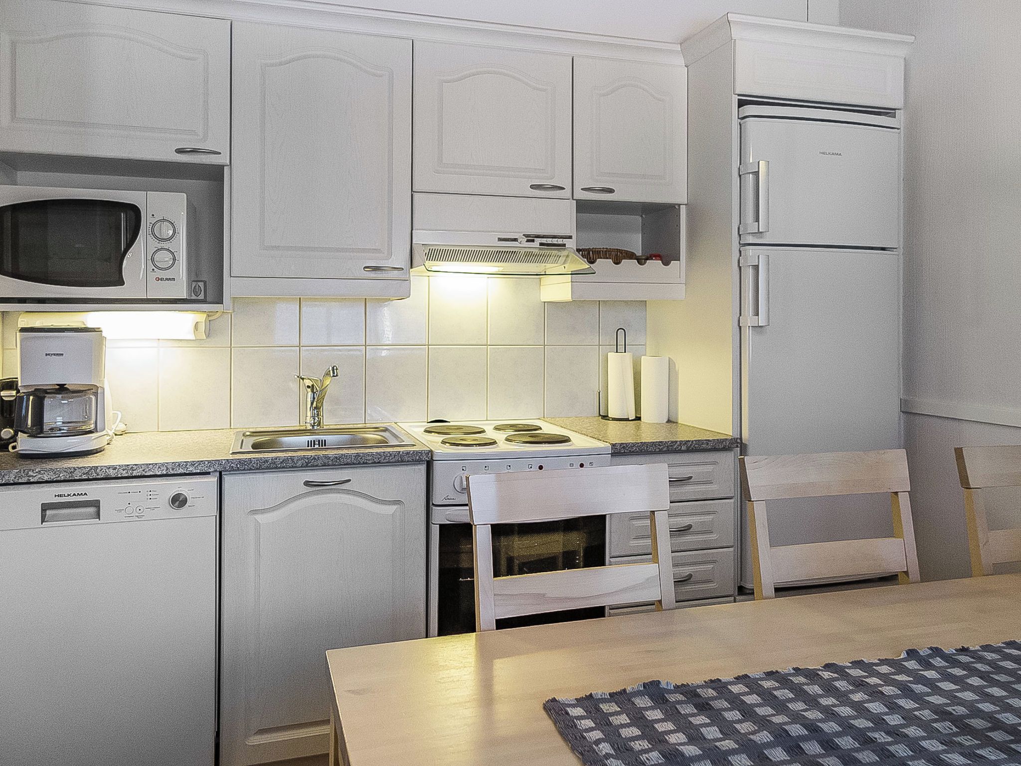 A compact kitchen with a microwave, stove, sink, and refrigerator.