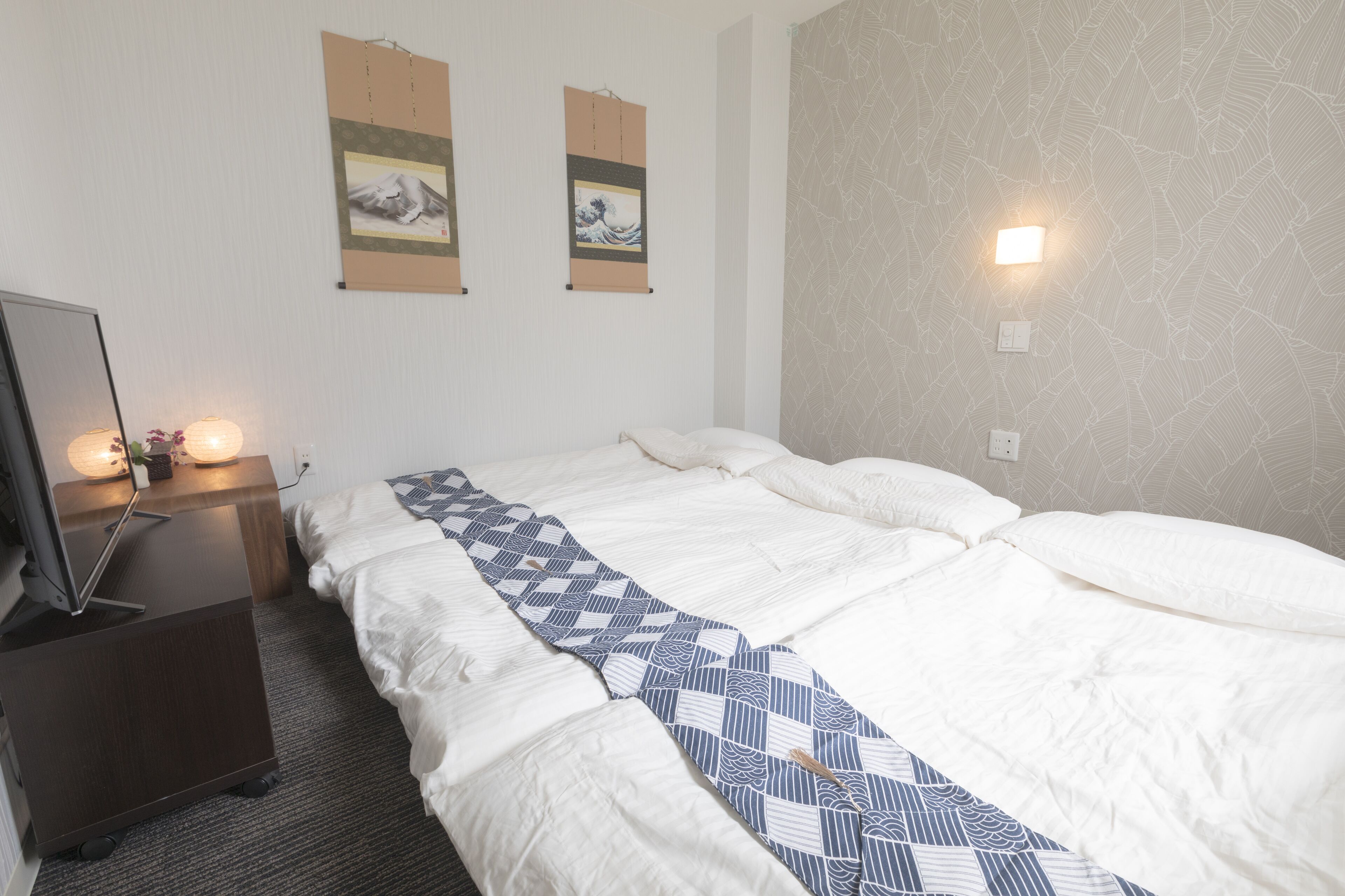 Habitación de hotel con una cama grande, un escritorio con computadora y dos obras de arte colgadas en la pared.