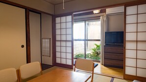 A traditional Japanese room with tatami flooring, a wooden table, and sliding shoji doors. - Kyomachiya IZO (Kyoto)