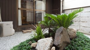 A garden with rocks, a palm tree, and a Fujitsu air conditioner. - Kyomachiya IZO (Kyoto)