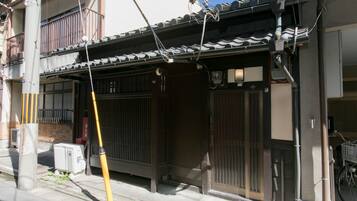 Traditional Japanese building with a tiled roof and a wooden entrance gate, featuring a small porch and a bicycle.
