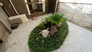 A small garden area with a gravel path, a potted plant, and a stone feature. - Kyomachiya IZO (Kyoto)