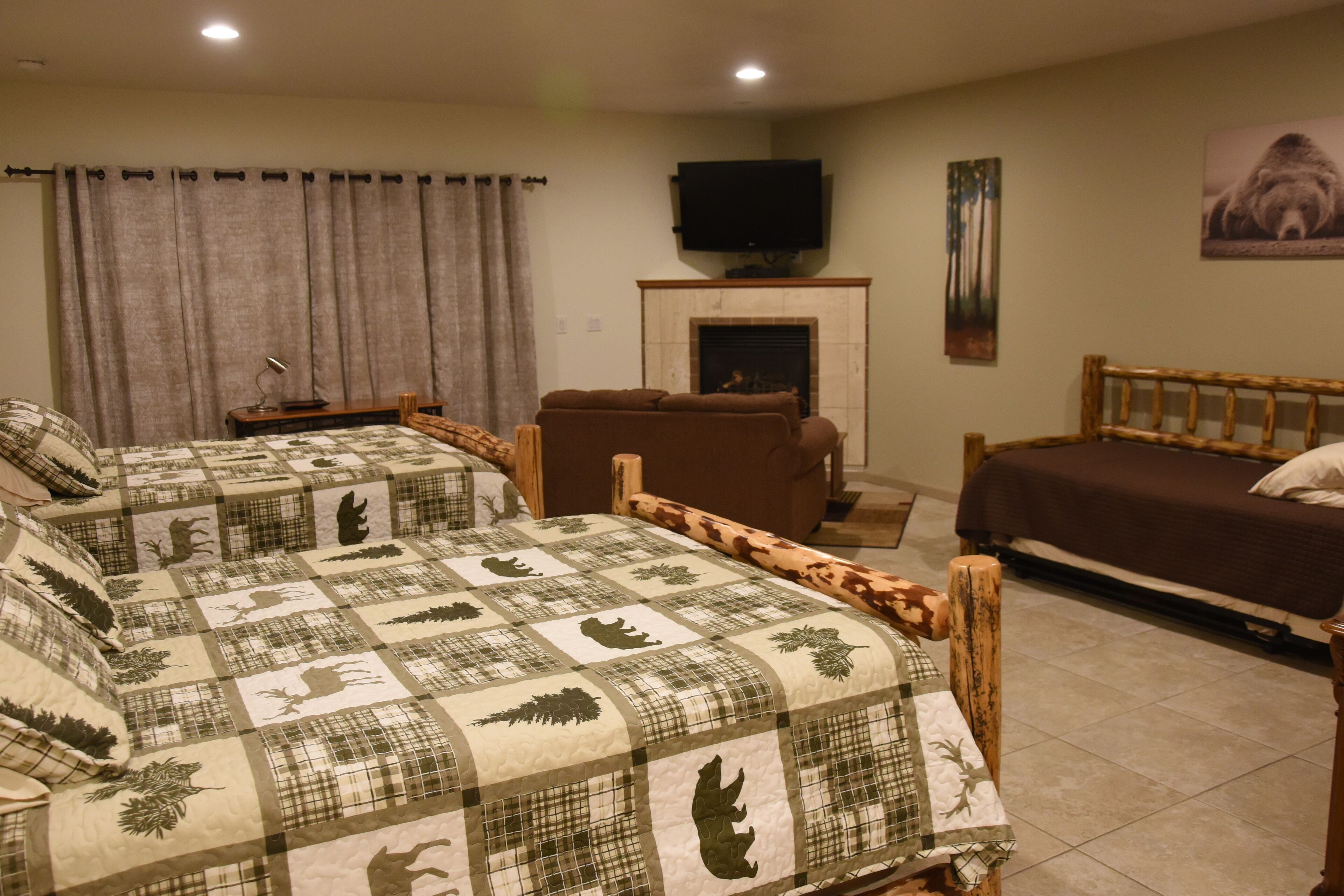 A hotel room with two beds, a television, a fireplace, and a painting on the wall.