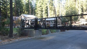 A bridge with a metal railing, a road, and a house with a number '74' on the side.