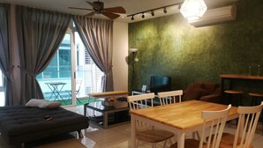 Un salon moderne comprenant un canapé, une table à manger, des chaises, un téléviseur et un ventilateur de plafond.