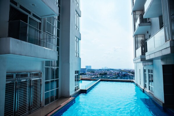 A modern building with a swimming pool, large windows, and a view of a cityscape.