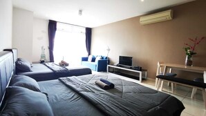 Une chambre d’hôtel avec deux lits, un bureau, une télévision et une fenêtre avec des rideaux.