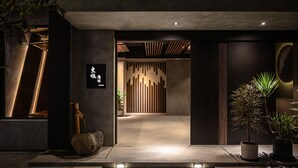A modern entrance with a stone pathway, wooden accents, and potted plants. - Yunoyado Onsen Hotspring Hotel Deyang (Jiaoxi)