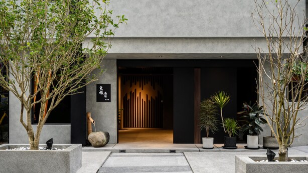 A modern building entrance with a concrete facade, a wooden door, and a pathway leading to the entrance. - Yunoyado Onsen Hotspring Hotel Deyang (Jiaoxi)