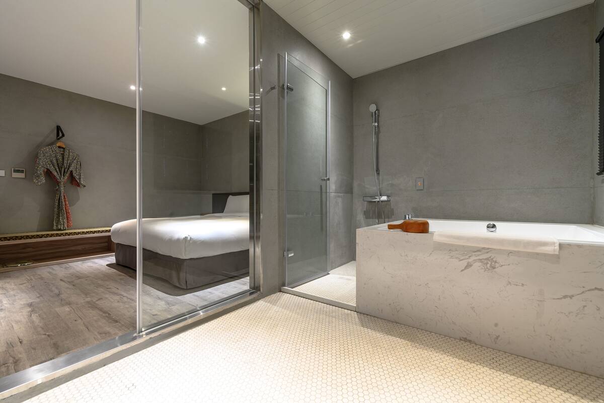 A modern bathroom with a glass shower enclosure, a large bathtub, and a separate shower area.