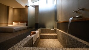 A modern hotel room with a large bed, a small seating area, a private bathroom with a shower, and a view of the outdoors. - Yunoyado Onsen Hotspring Hotel Deyang (Jiaoxi)