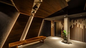A modern interior with a wooden bench, a potted plant, and a wall with vertical wooden slats. - Yunoyado Onsen Hotspring Hotel Deyang (Jiaoxi)