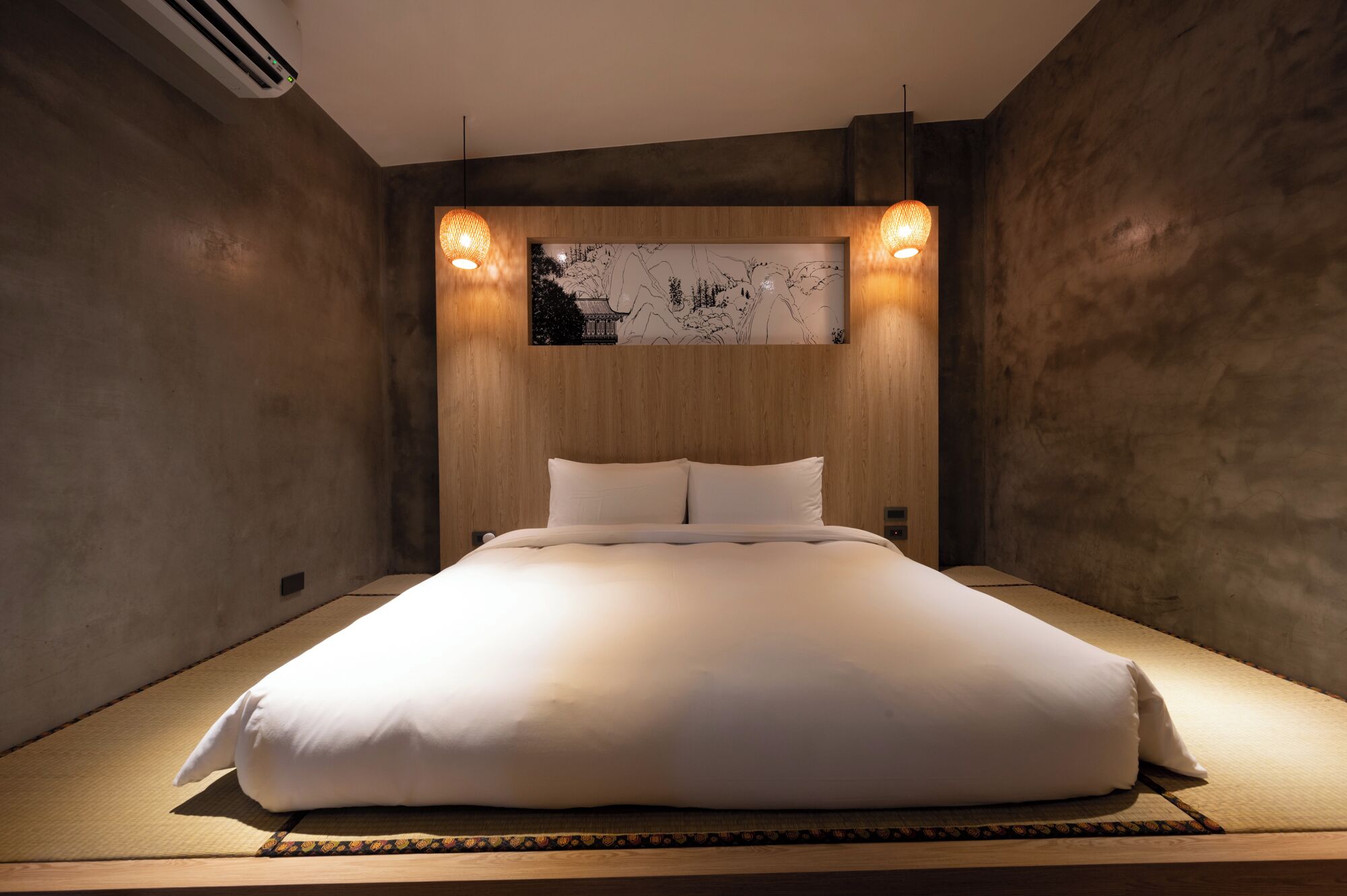 A modern bedroom with a large bed, wooden headboard, and a wall-mounted artwork.