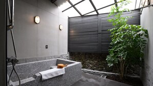 A modern bathroom with a stone bathtub, a towel, and a plant. - Yunoyado Onsen Hotspring Hotel Deyang (Jiaoxi)