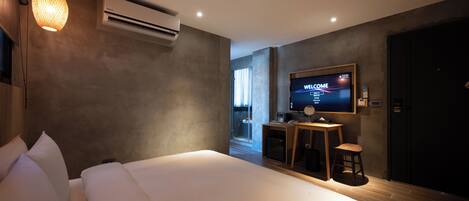 Una habitación de hotel moderna con una cama grande, un televisor en la pared y un equipo de aire acondicionado.