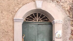 A stone wall with a green door and a decorative metal grille above it.