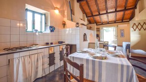 A kitchen with a tiled backsplash, a gas stove, and a dining area with a striped tablecloth.