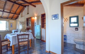 A dining area with tables set for two, wooden chairs, a checkered floor, and a rustic ceiling.