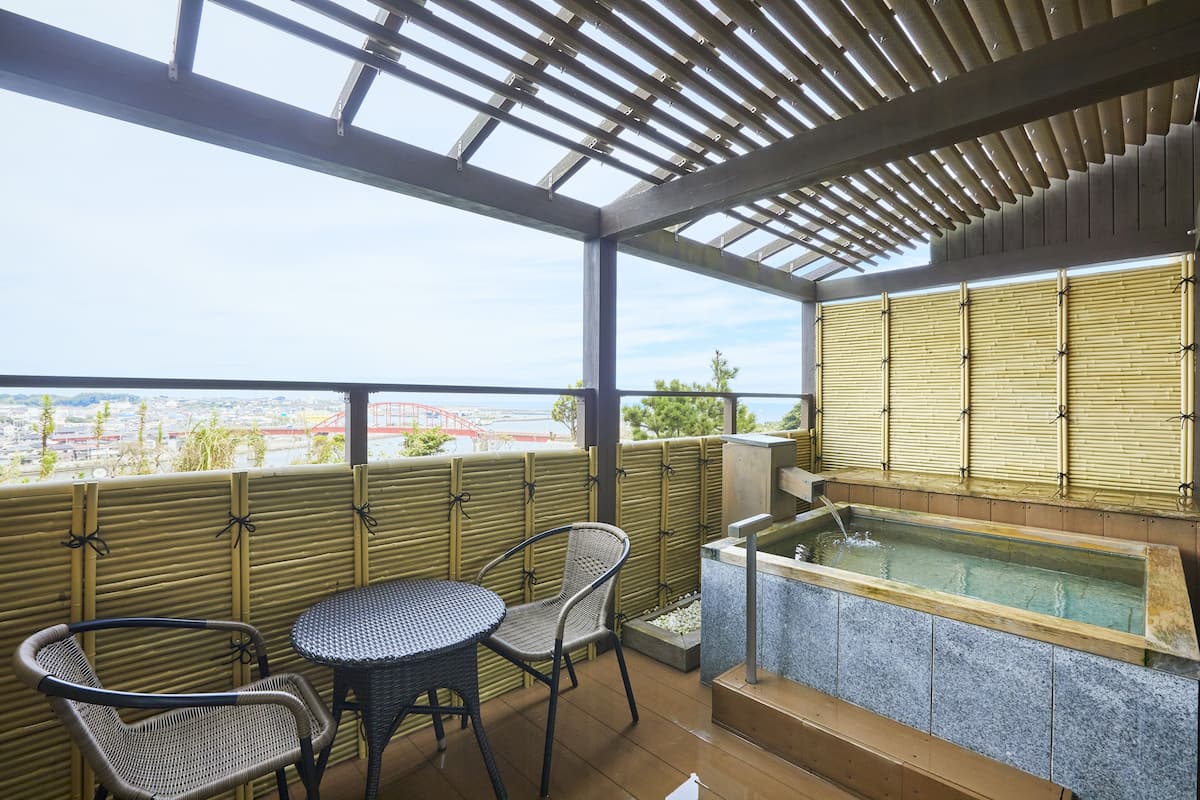 A covered outdoor area with a table and chairs, a small water feature, and a view of a bridge.