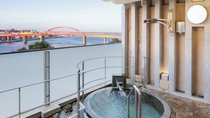 Un jacuzzi con vista a un puente rojo y un paisaje urbano al fondo.
