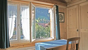 Um quarto com mesa e cadeira de madeira, uma janela com cortinas e um radiador.