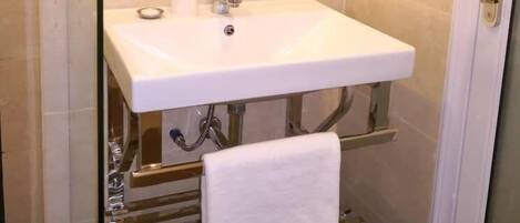 A bathroom with a white sink, a mirror above it, and a towel hanging on a rack.