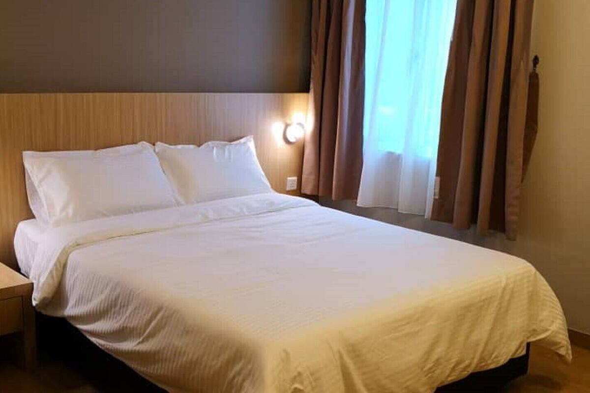 Cama bem arrumada com lençóis brancos em um quarto de hotel.