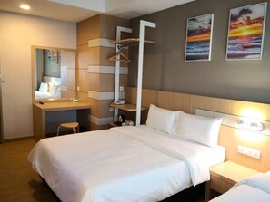 A modern hotel room with a bed, a desk with a chair, a mirror, and artwork on the wall. - Walk In Hotel (Kota Kinabalu)