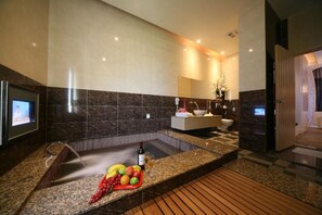 A modern bathroom with a large bathtub, a vanity with a mirror, and a television mounted on the wall. - Hmulan Motel (Taichung)