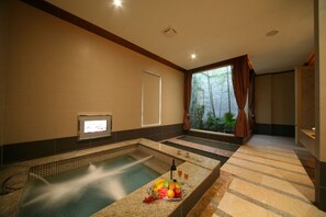 A spa area with two hot tubs, a fruit bowl, and a view of greenery through the window. - Hmulan Motel (Taichung)