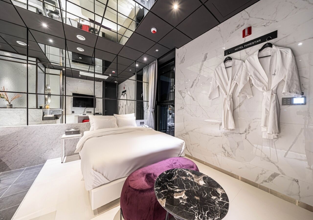 Una habitación de hotel moderna con una cama grande, una pared de mármol y una bata colgada en la pared.