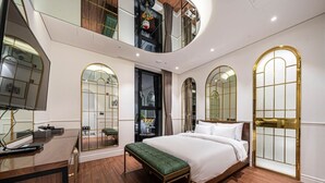 A modern bedroom with a large bed, a desk, and a bench. There is a balcony with a view of the city. - Forestar (Seoul)