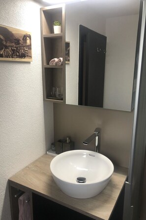 A bathroom with a white sink, a mirror, and a shelf with towels. - Cresta di Saas by Interhome (Saas-Grund)