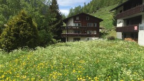Ein Hotel mit zweistöckiger Bauweise, Balkonen und einem Garten mit gelben Blumen.