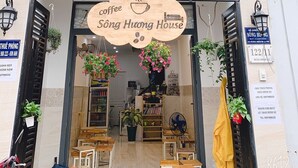 A coffee shop named Sòng Huong House with a signboard, outdoor seating, and hanging plants. - Song Huong House (Ho Chi Minh City)