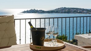 Une terrasse avec vue sur la mer, une bouteille de champagne et des verres sur un plateau.