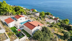 Un complexe de villas en bord de mer, composé de plusieurs bâtiments, doté d’une piscine et offrant une vue sur la mer.
