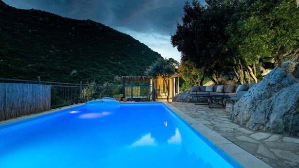 A swimming pool with a stone deck, a seating area with cushions, and a view of a mountainous landscape. - Amazing home in Ploce with sauna (Ploce)