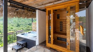 A spa area with a hot tub and wooden cabinets, set against a backdrop of lush greenery. - Amazing home in Ploce with sauna (Ploce)