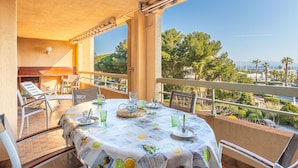 Varanda com mesa posta para refeições, com vista panorâmica para árvores e um porto.
