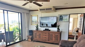 Ein Wohnzimmer mit einem Glastisch, einer Couch, einem Fernseher und einem Schrank.