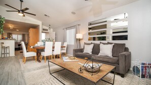 A modern living room with a sofa, coffee table, and dining area. - THE ONE!! Spa⁕Heated Pool⁕Fire Pit ⁕Putting Green  (Peoria)