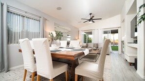 A dining area with a wooden table, white chairs, and a ceiling fan. - THE ONE!! Spa⁕Heated Pool⁕Fire Pit ⁕Putting Green  (Peoria)