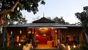 A traditional building with a red interior, a tiled roof, and a central staircase leading to a door. - The Breath Chiangdao (Chiang Dao)