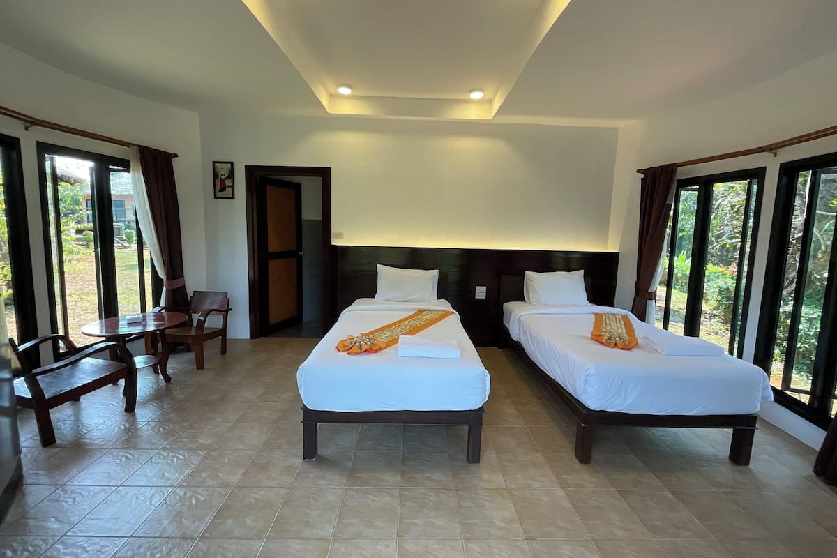 A hotel room with two beds, a desk, and a chair.