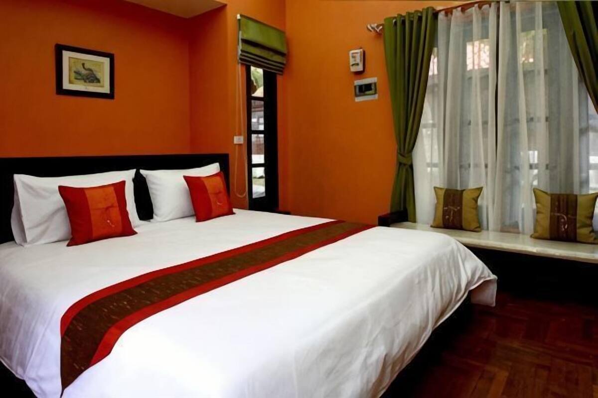 A hotel room with a large bed, a window with curtains, and a picture on the wall.
