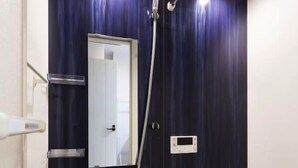 Uma casa de banho moderna com parede azul escura, uma banheira branca, um chuveiro manual e um painel de controlo fixado na parede.